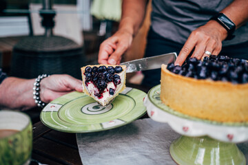 midsection of women serving slice of blueberry cake