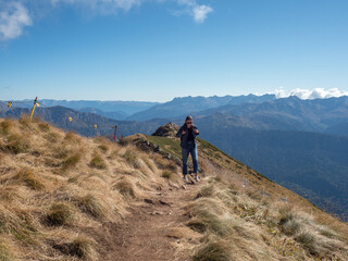 Fototapeta premium Hiking in the mountains, a young female tourist with a backpack is walking along