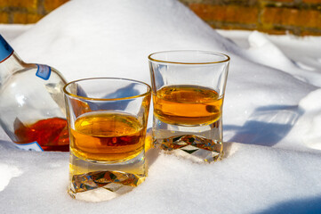 Glasses of cold scotch single malt whisky on white snow