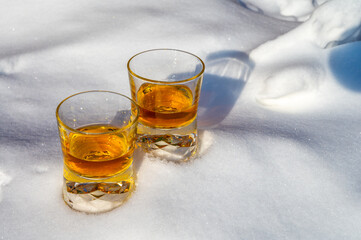 Glasses of cold scotch single malt whisky on white snow