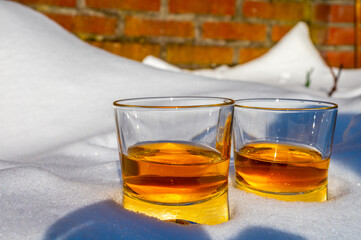 Glasses of cold scotch single malt whisky on white snow