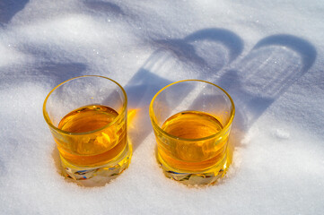 Glasses of cold scotch single malt whisky on white snow