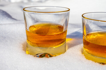 Glasses of cold scotch single malt whisky on white snow