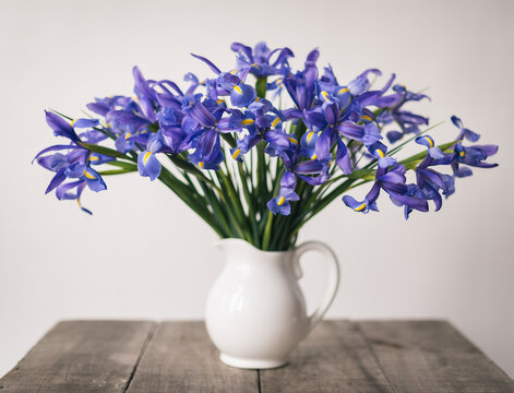 Close-up of purple flowers arranged in vase on wooden table by wall