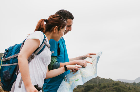 Friends analyzing map while standing against clear sky
