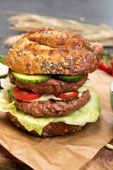 Tasty vegetarian vegan lunch with double decker hamburger made from plant based soya beans burger, organic bun with seeds and fresh vegetables