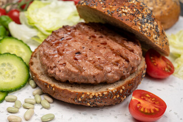 Making tasty vegetarian vegan hamburger from plant based soya beans burger, organic bun with seeds and fresh vegetables
