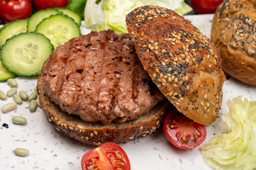 Making tasty vegetarian vegan hamburger from plant based soya beans burger, organic bun with seeds and fresh vegetables