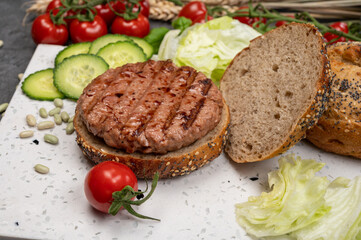 Making tasty vegetarian vegan hamburger from plant based soya beans burger, organic bun with seeds and fresh vegetables