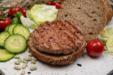 Making tasty vegetarian vegan hamburger from plant based soya beans burger, organic bun with seeds and fresh vegetables