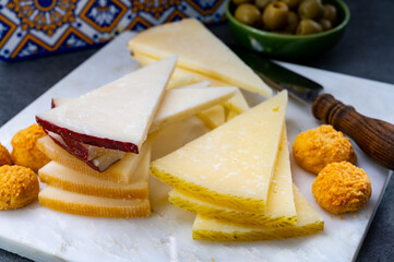 Spanish snacks tapas, variety of sliced goat, sheep, manchego cheeses, green olives