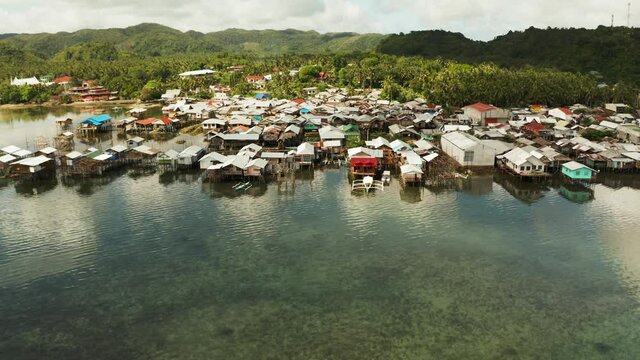 Fishing village with wooden houses standing on stilts in the sea from above. Dapa, Siargao, Philippines.