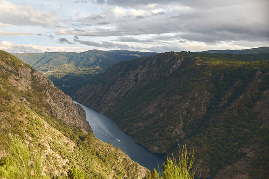 Boat crossing a river between mountains cloudy day sunny aerial