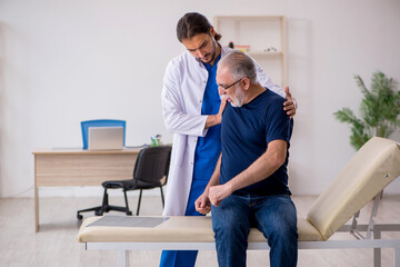 Old male patient visiting young male doctor chiropractor