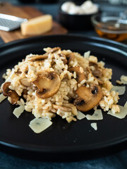 Risotto with champignon and parmesan on black table 
