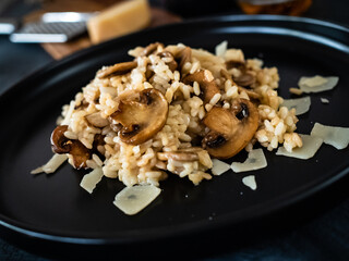 Risotto with champignon and parmesan on black table 
