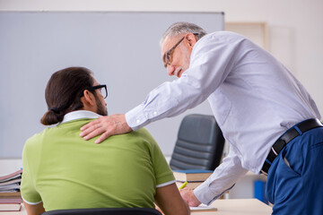 Fototapeta premium Old male teacher and young male student in the classroom