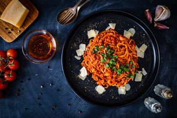 Spaghetti bolognese with minced pork meat and parmesan on black table