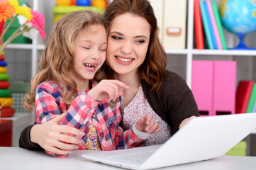 Naklejka premium mother and daughter using laptop together