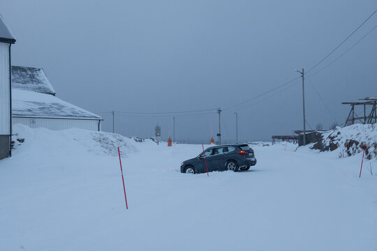 Tourist rental car stuck in ditch on side of road on snow covered winter roadway, near Reine, Lofoten Islands, Norway