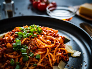 Spaghetti bolognese with minced pork meat and parmesan on black table