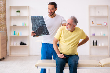 Old male patient visiting young male doctor chiropractor