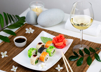 Dinner in a Japanese restaurant by candlelight, rolls, sushi and white wine