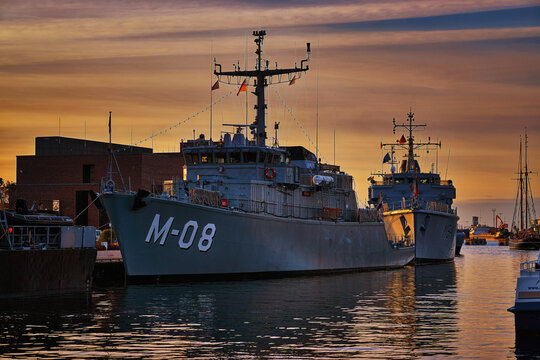 Military boat in the old harbor of Wismar with sunset over the Baltic Sea in the background.