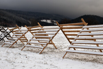 anti snow wooden fence on the meadow in winter mountains