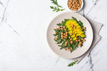 Healthy vegetarian food: cooked chickpeas with fresh arugula and avocado