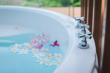 Bathtub outside at the balcony with tropical flowers in luxury hotel.