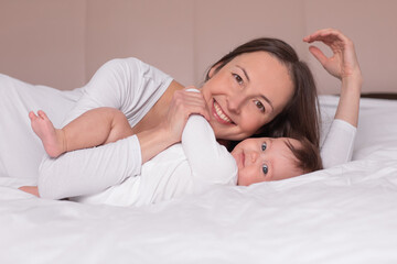 Obraz na płótnie Canvas happy woman with baby lying on the bed