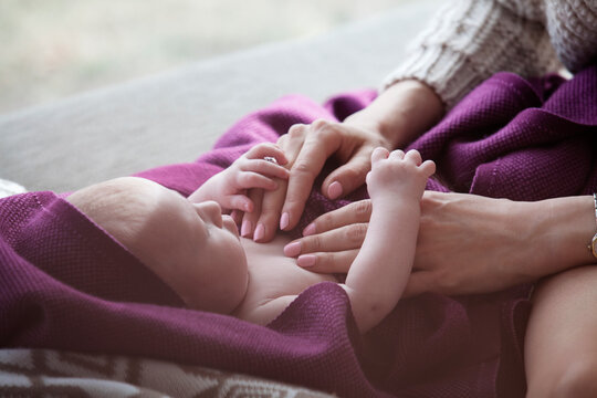Cropped image of woman touching baby girl lying on sofa at home