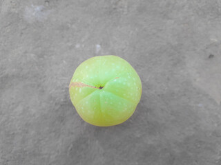 a beautiful green coloured amala's fruit on brown background, it's uses in production of medicine