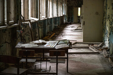 old rotten school desk with old books in abandoned school in lost city after catastrophe 