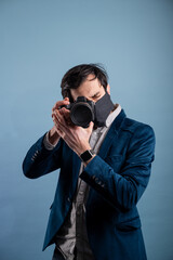 Obraz premium Portrait of positive photographer, man with medical mask holding professional digital dslr camera