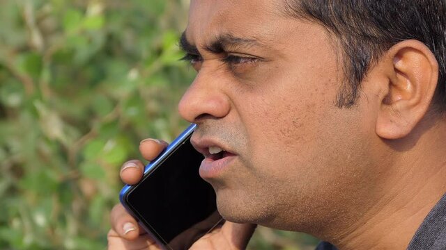 Close portrait shot of an angry indian man talking and fighting with someone over the cell phone