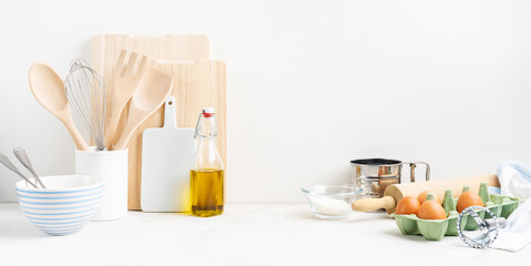 Kitchen background mockup with eggs, rolling pin, bowls for cooking and baking utensils on the table on white background. Blank space for a text, home kitchen decor concept. Wide banner.