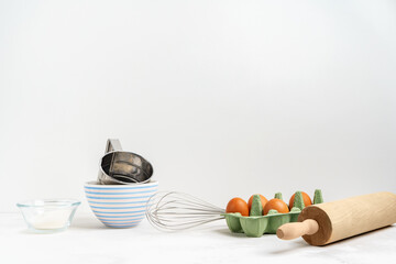 Fototapeta na wymiar Kitchen background for mockup with eggs, rolling pin, bowls for cooking and baking utensils on the table on white background. Blank space for a text, home kitchen decor concept. Wide banner.