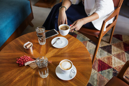 Midsection of businesswoman holding coffee cup at table in hotel lobby