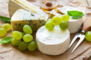 Various types of cheese, basil and grapes