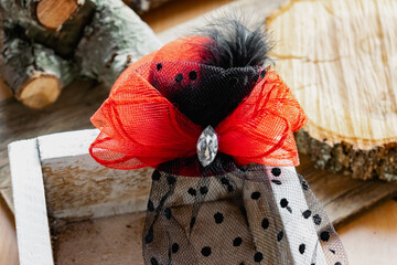 Decorative hat on a hair clip with a red bow and a black veil. Accessory for a themed party or...