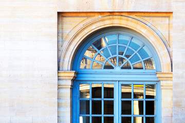 Facade of the classic building, architectural background. Wooden blue window with arch, reflection of city in glass