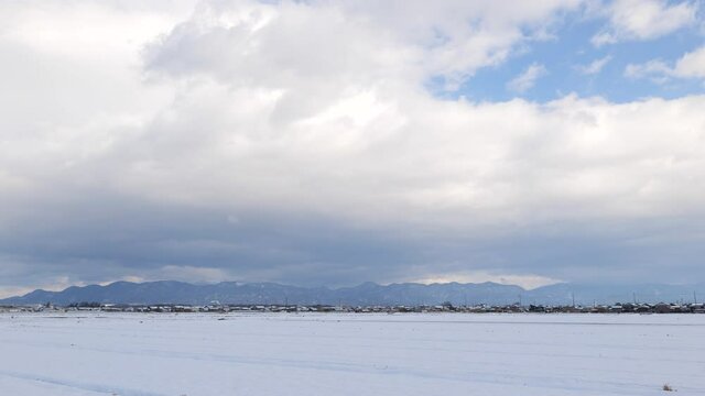 Shiga Prefecture in winter, huge clouds and the Suzuka Mountains seen beyond the snowfield.