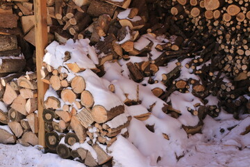 Schnee bedeckt das Kaminholz in einem Holzschuppen