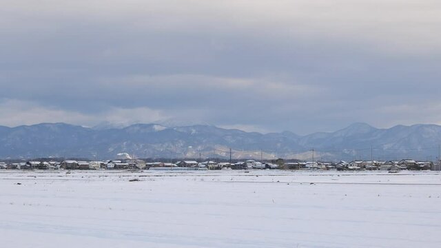 Shiga Prefecture in winter, huge clouds and the Suzuka Mountains seen beyond the snowfield.