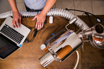 Overhead view of owner using laptop and coffee roaster at table