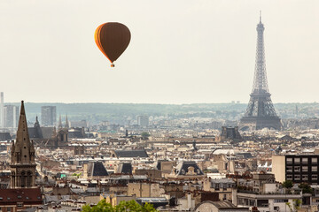 Hot air balloon flying over cityscape with Eiffel Tower in background