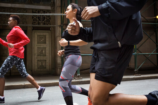 Side view of determined athletes jogging on city street