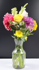 VASE WITH BEAUTIFUL COLORFUL BRIGHT FLOWERS ISOLATED IN DARK BACKGROUND.